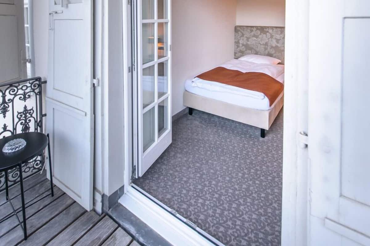 Une chambre à coucher avec un lit, une chaise et une porte donnant sur une autre pièce.