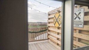 Een houten terras met uitzicht op een bord van een privé-spoorwegovergang.