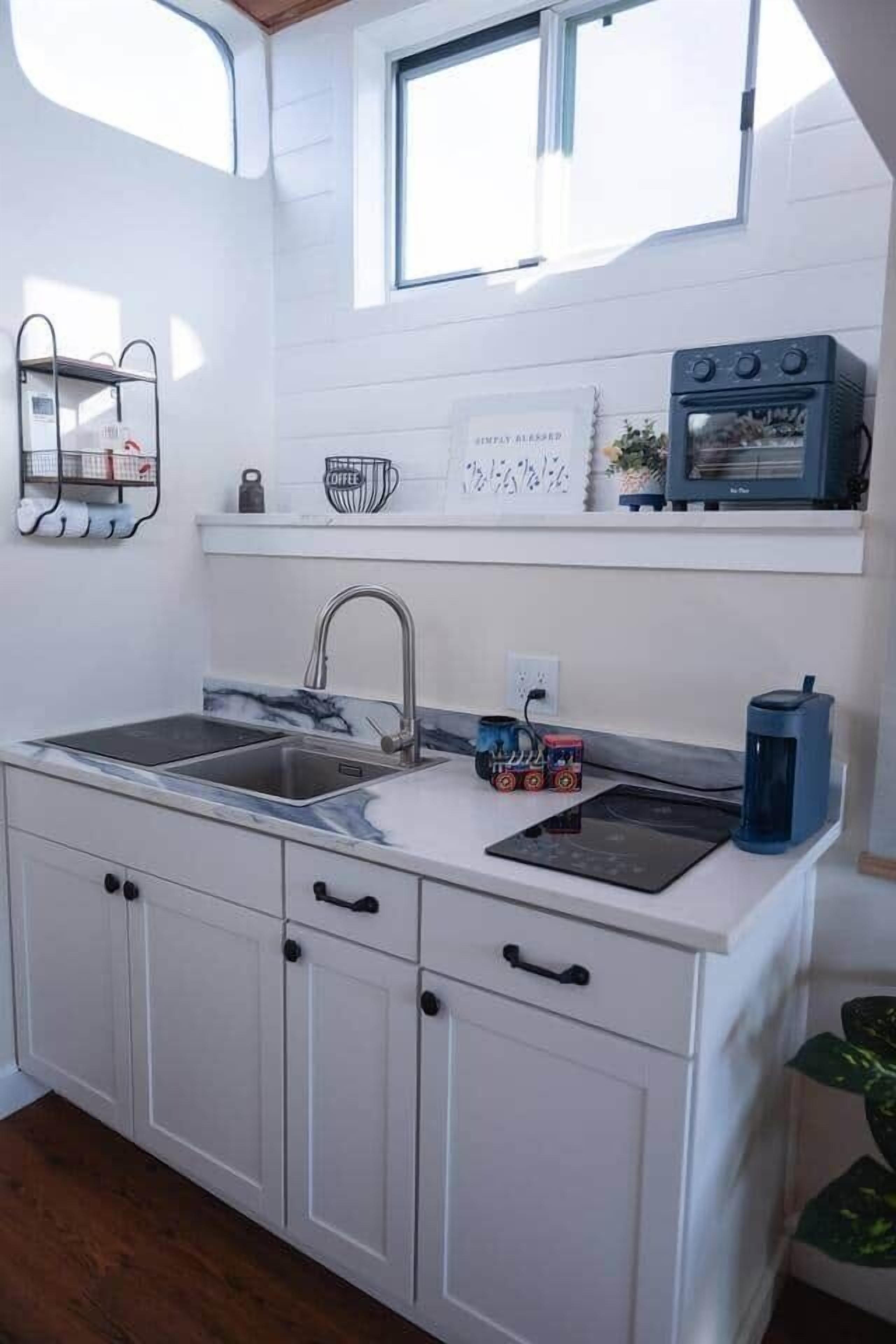 Cocina compacta con pileta, estufa y pequeño sector para café.