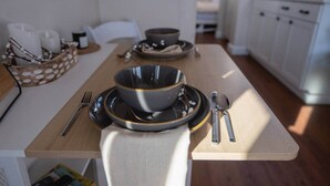 Een eettafel gedekt met kommen, borden en bestek in een moderne keuken.