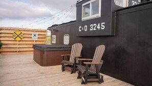 Een privé-hut met nummer C&0 3245, een hottub en twee Adirondack-stoelen op een houten terras.