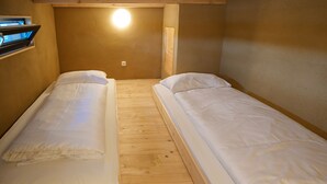 Una sistemazione piccola e compatta con due letti singoli, pavimento in legno e luce a parete.