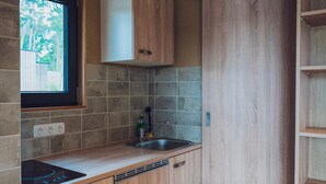 Una cucina con mobili in legno, piano cottura integrato, lavandino e finestra.