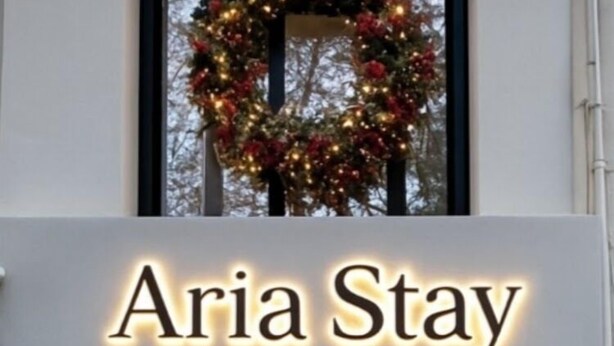 Der Eingang von Aria Stay mit einem Weihnachtskranz über der Tür, zwei beleuchteten Laternen zur Seite und ein Weihnachtsbaum auf jeder Seite des Eingangs.