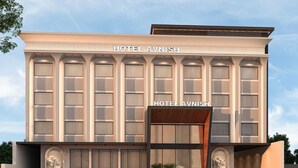 Un hôtel moderne, doté d’une entrée imposante, de grandes fenêtres et d’une voiture rouge garée devant.