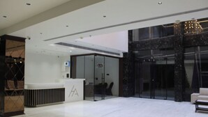 Un hall d’hôtel moderne avec un comptoir d’accueil, une entrée avec une porte en verre et un espace salon.