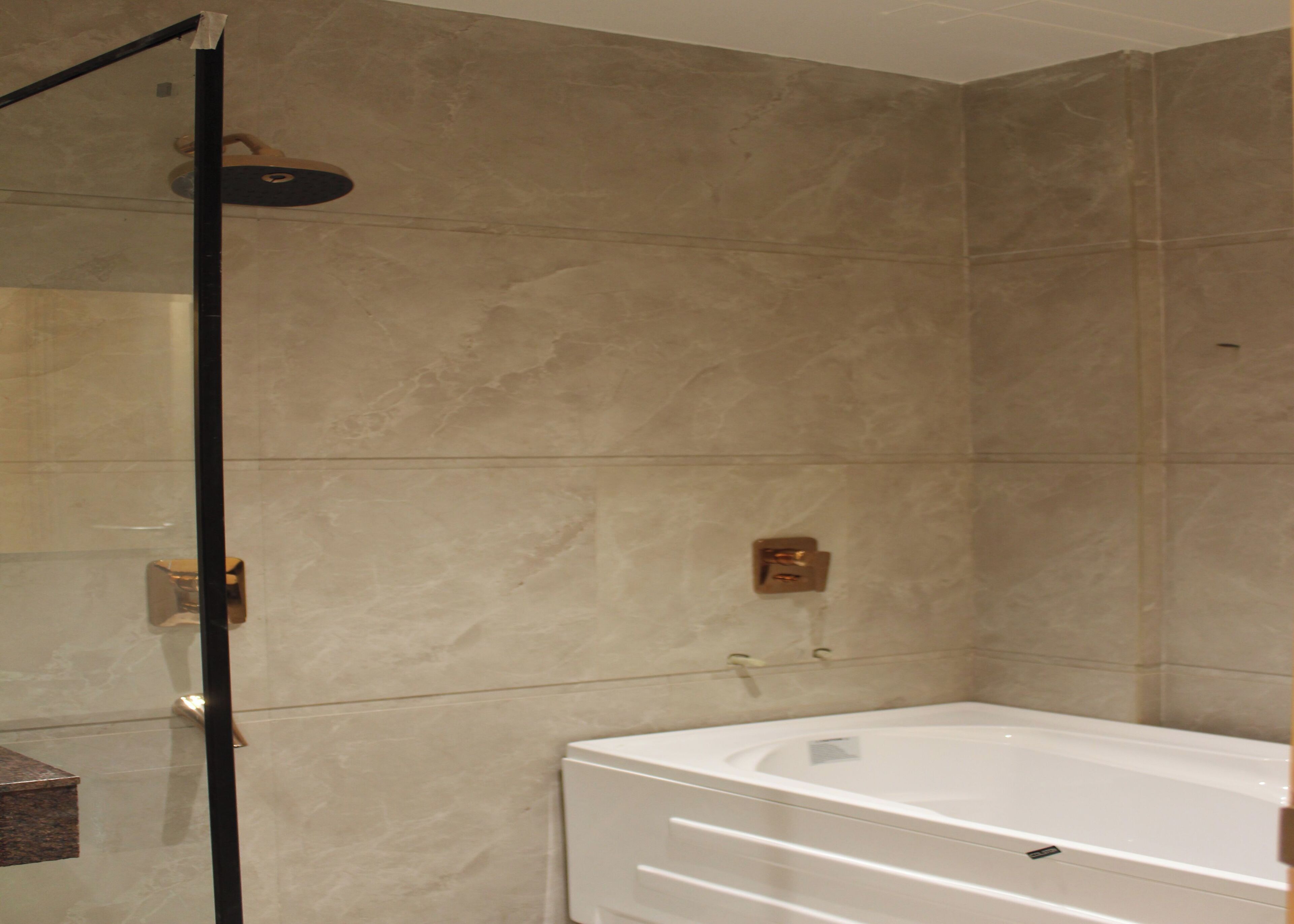 Un baño con baldosas de mármol color crema, una bañera blanca y una cabina de ducha de vidrio.