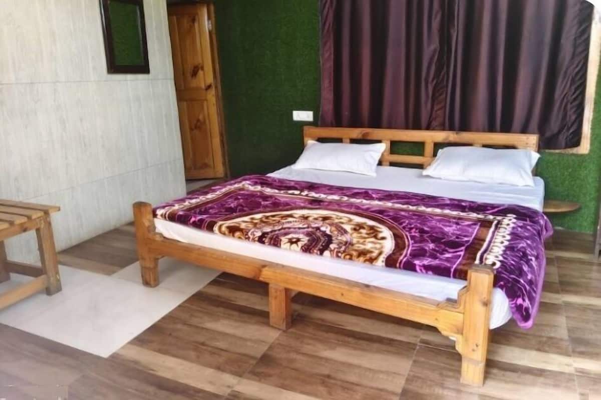 A wooden bed with a patterned bedspread, a wooden nightstand, and a green wall.