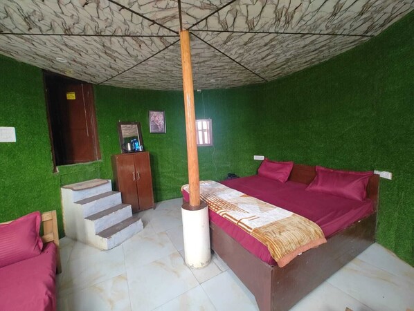 A room with green walls, a bed with a red bedspread, a wooden wardrobe, and a staircase.