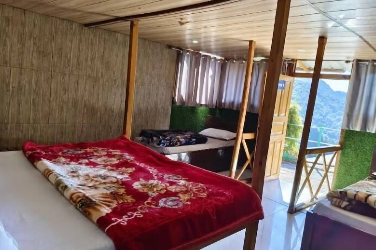 A room with a bed, a small table, and a view of the outdoors.