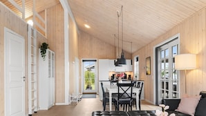 A spacious living area with a black leather sofa, a white coffee table, and a dining area with a black table and chairs. - "Rixa" - 350m from the sea by Interhome (Frørup)