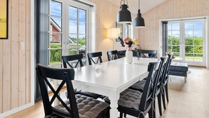 A dining area with a white table, black chairs, and a vase of flowers. There are large windows and a view of the outside. - "Rixa" - 350m from the sea by Interhome (Frørup)