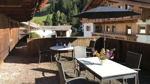 A wooden chalet with a patio area featuring a table, chairs, and an umbrella. - Fichtenblick by Interhome (Wildschönau)