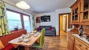 A dining area with a table set for two, a sofa, and a television in the background. - Fichtenblick by Interhome (Wildschönau)