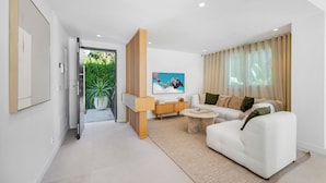 Ein modernes Wohnzimmer mit einem weißen Sofa, einem Couchtisch und einem an der Wand montierten Fernseher.