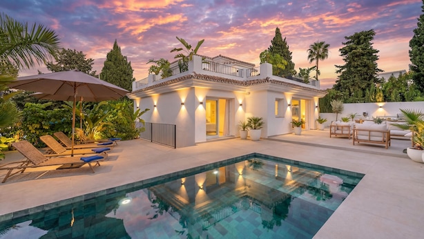 Ein modernes Haus mit Swimmingpool, Sitzgelegenheiten im Freien und einer gut beleuchteten Terrasse.