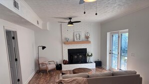 Una sala de estar con chimenea, un sofá, una mesa de centro y un ventilador de techo.