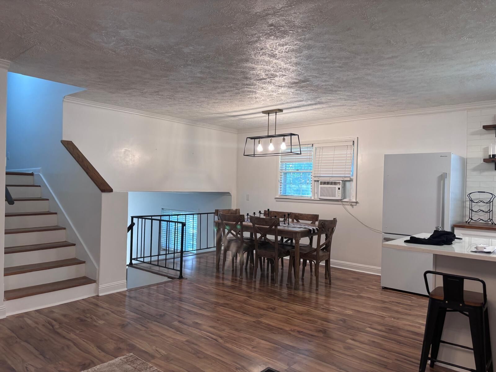 Une cuisine moderne avec un coin repas, un plancher en bois et un escalier.