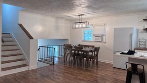 Una cocina moderna con comedor, piso de madera y una escalera.
