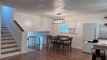 Une cuisine moderne avec un coin repas, un plancher en bois et un escalier.