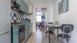 Une cuisine compacte équipée d’une cuisinière, d’un four et d’un évier, qui donne sur un coin repas avec une table et des chaises.