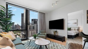 A modern living room with a large window, a sofa, a coffee table, a TV, and a bed. - The Queensbridge Contemporary Nostalgia. Heated pool, Gym, Sauna, Steam, Bar (Melbourne)