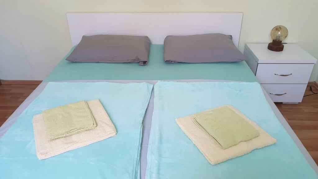 Una cama con dos almohadas, una mesita de noche con lámpara y una cómoda.