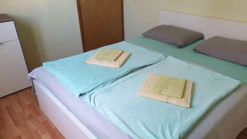 A double bed with light blue bedding and two pillows, one grey and one brown.