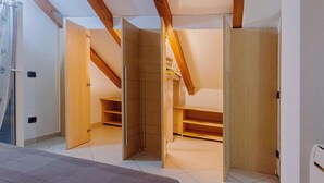 Una habitación con techo inclinado, vigas de madera y estanterías empotradas.