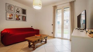 Una sala de estar con un sofá rojo, una mesa de centro de madera y un ventanal con cortinas.