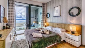 Ein modernes Schlafzimmer mit Bett, Nachttischen, einem Schreibtisch und Blick ins Freie.