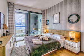 A modern bedroom with a bed, bedside tables, a desk, and a view of the outdoors. - Holiday apartment with a beautiful pool (Njivice)