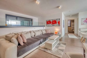 A modern living room with a sofa, a coffee table, and a painting on the wall. - Holiday apartment with a beautiful pool (Njivice)
