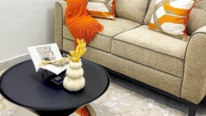 Una sala de estar con un sofá, dos almohadas, una mesita con un jarrón y un libro.