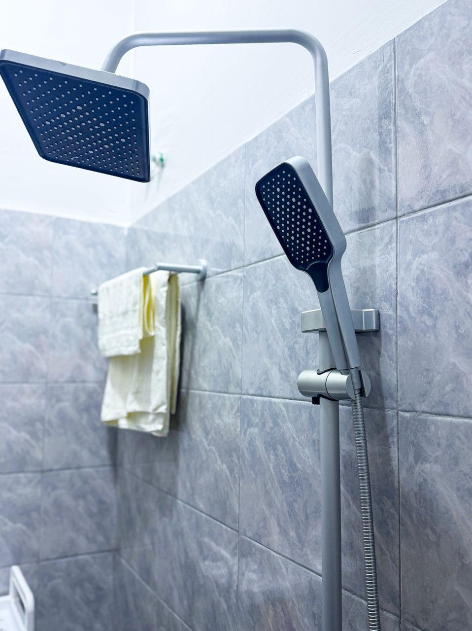 Ein Duschbereich mit einer Handbrause und einem fest installierten Duschkopf an der Wand.
