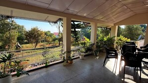 A covered outdoor area with tiled flooring, potted plants, and outdoor furniture. - Summer valley cottage (Mant Khas)