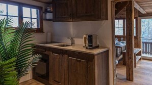 A rustic kitchen with wooden cabinets, a sink, and a coffee maker.