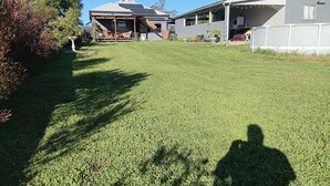 A residential property with a well-maintained lawn, a covered outdoor seating area, and a house with solar panels. - The Wonky House (Bowraville)