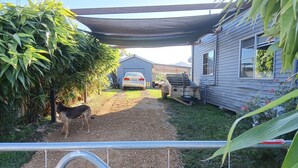 A gravel driveway leading to a house with a car parked in the driveway. - The Wonky House (Bowraville)