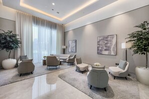 A modern living room with a large window, a sofa set, two armchairs, a coffee table, and two floor lamps. - Cozy 1BR 5 minutes walk from Burj Khalifa (Dubai)