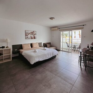 A modern hotel room with a large bed, a desk, and a balcony with a view. - Nissi Avenue 64 Studio 1 - Luxcyservices (Ayia Napa)
