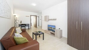 Ein modernes Wohnzimmer mit einem braunen Ledersofa, einem kleinen Couchtisch, einem Fernseher und einem Kleiderschrank.