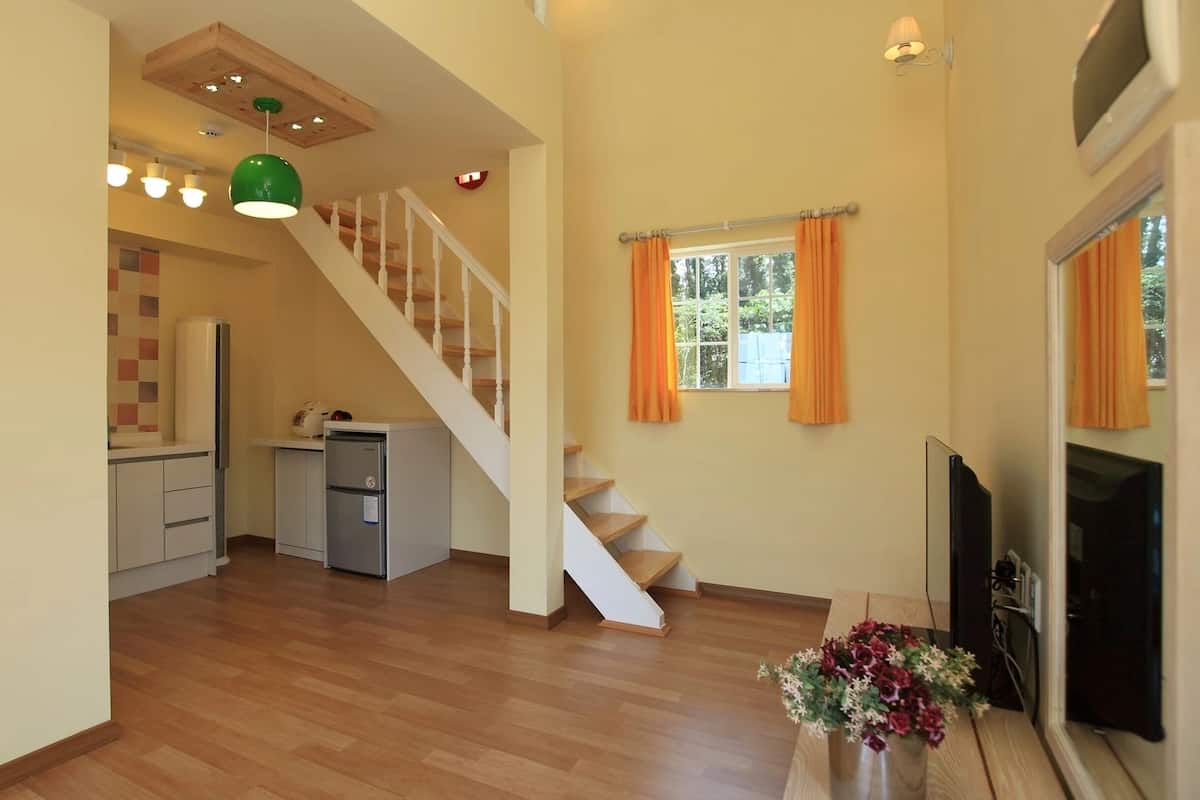Amplia sala de estar con una escalera de madera, una cocina equipada con electrodomésticos modernos y una chimenea.