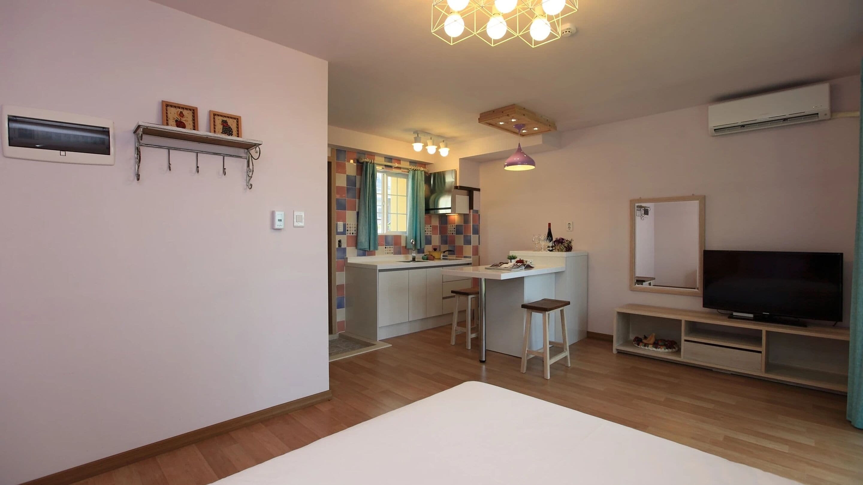 Ein modernes Wohnzimmer mit Fernseher, einem Essbereich und einer dahinterliegenden Küche, mit Holzboden.