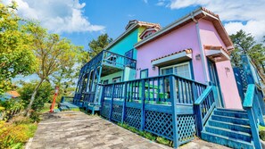 Una casa de dos pisos con una escalera de madera que lleva a un porche azul.