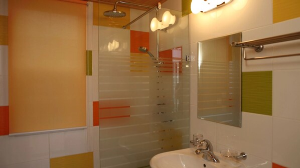 Une salle de bain avec une douche à parois de verre, un lavabo avec un miroir et un porte-serviettes.