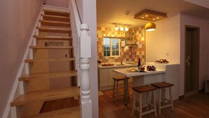 Een keuken met een houten trap, een geruit spatwand en een klein eiland met krukken.
