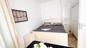 Ein Schlafzimmer mit einem Bett, Nachttischen, einem Kleiderschrank und einem Bild an der Wand.