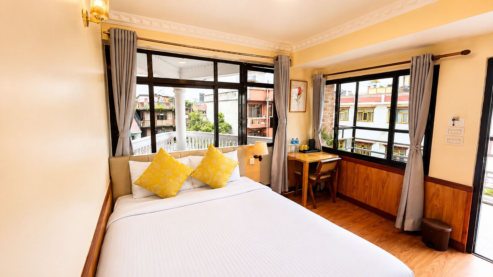 A hotel room with a bed, a desk, and a view of buildings outside.