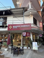 El exterior del Hotel Boudha Mandala, con un letrero, zona de estar al aire libre y plantas en macetas.